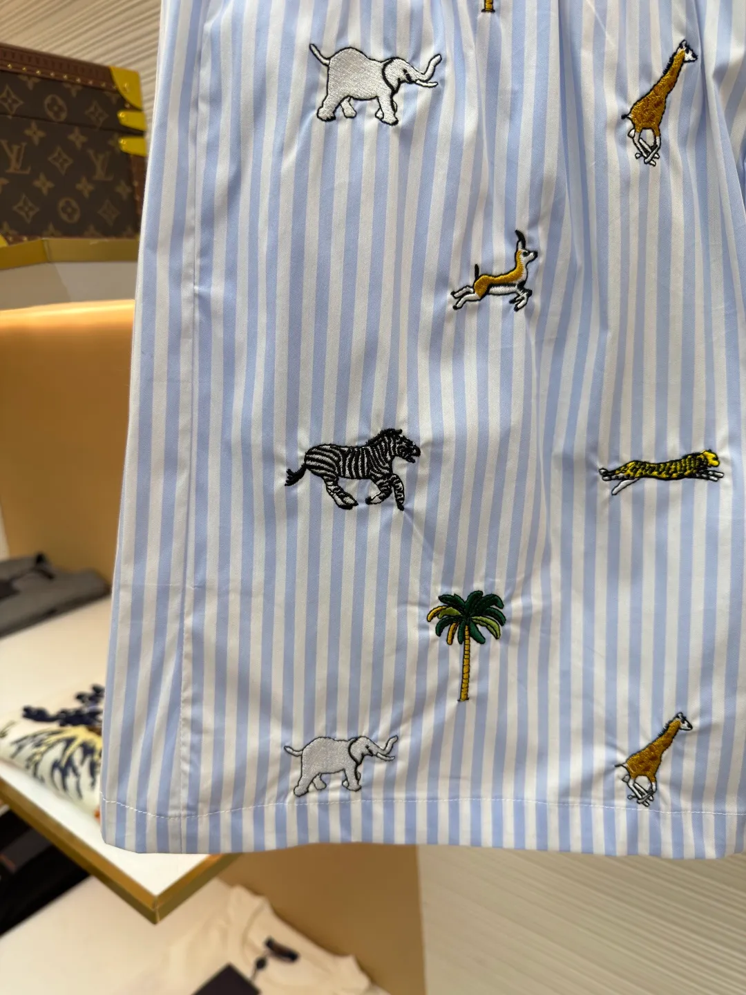 LOUIS VUITTON Animal and plant nostalgic style embroidered striped shorts ●Original version: purchased and developed by 14616 ●Item number: 1682542-A75 ●Fabric: cotton fabric ●Technology: embroidery production ●Color: blue ●Version: fitted version ●Weight: about 205 grams ●Size: S-M-L-XL ●Description: Made of high-count pure cotton poplin fabric. After pre-washing process, it feels smooth and breathable. It has both drape and stiffness, and is not easy to wrinkle and deform. The blue and white vertical stripes on the body are woven with yarn-dyed technology, and the texture is clear and does not fade. The animal and coconut tree patterns are presented with sophisticated embroidery technology. The embroidery threads are full of color and the stitches are dense. The patterns are three-dimensional and vivid, forming a rich visual hierarchy with the stripe base. The shirt has a Cuban collar style, with smooth necklines, custom mother-of-pearl buttons at the placket, and a warm texture. The overall shape is loose, the shoulder joints are straight and fine, the cuffs are cuffed with exquisite craftsmanship, custom accessories and three logos are complete, and the details are full of luxury craftsmanship. It is suitable for casual vacations and daily outings, etc. The overall wiring is straight and delicate, the fabric is comfortable and soft, and the color is consistent without color difference. It can be matched with the same style to create a fashionable look and control various occasions. Customized accessories, complete with three standards, same style for men and women!
